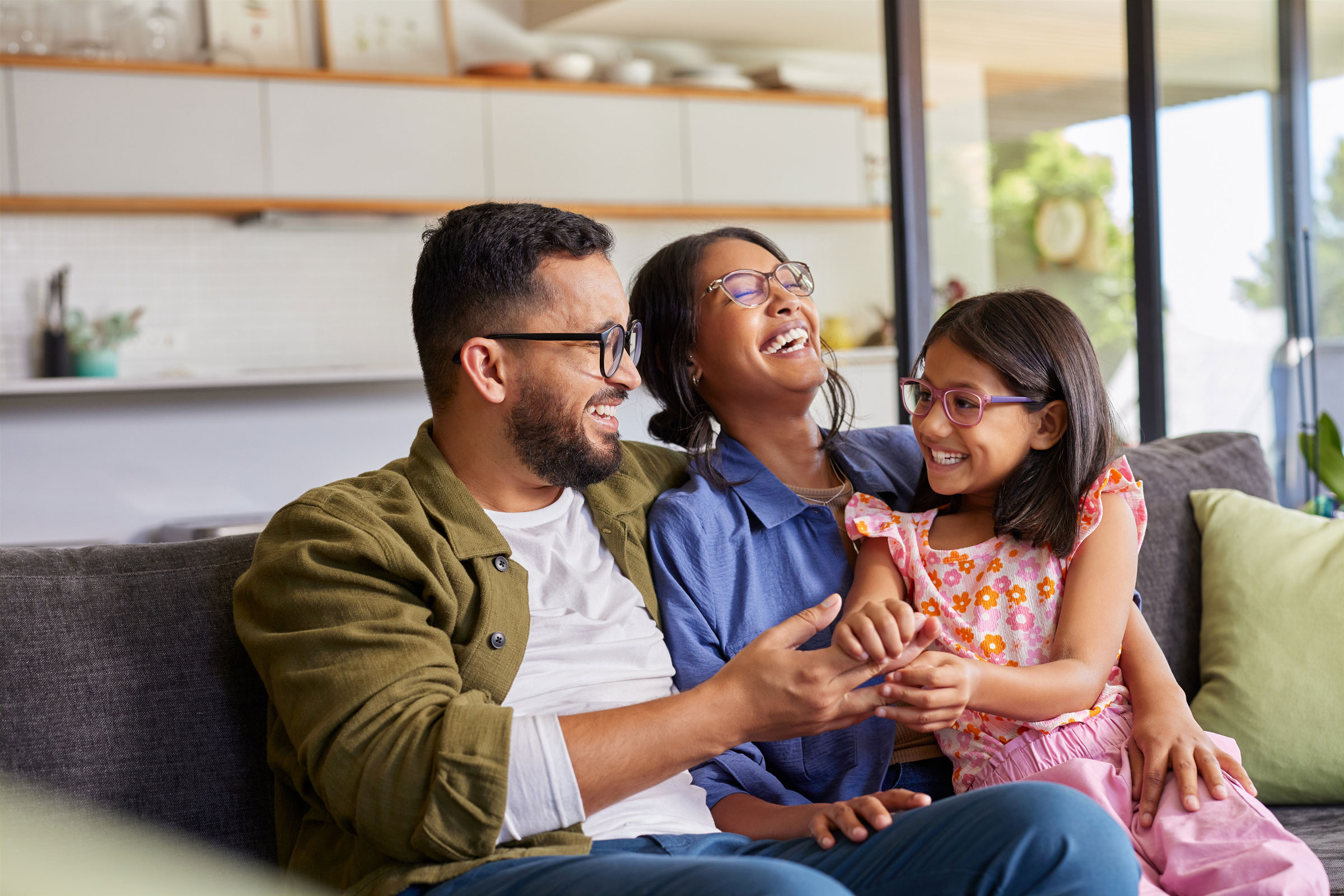 A family sits on the couch and laughs together.