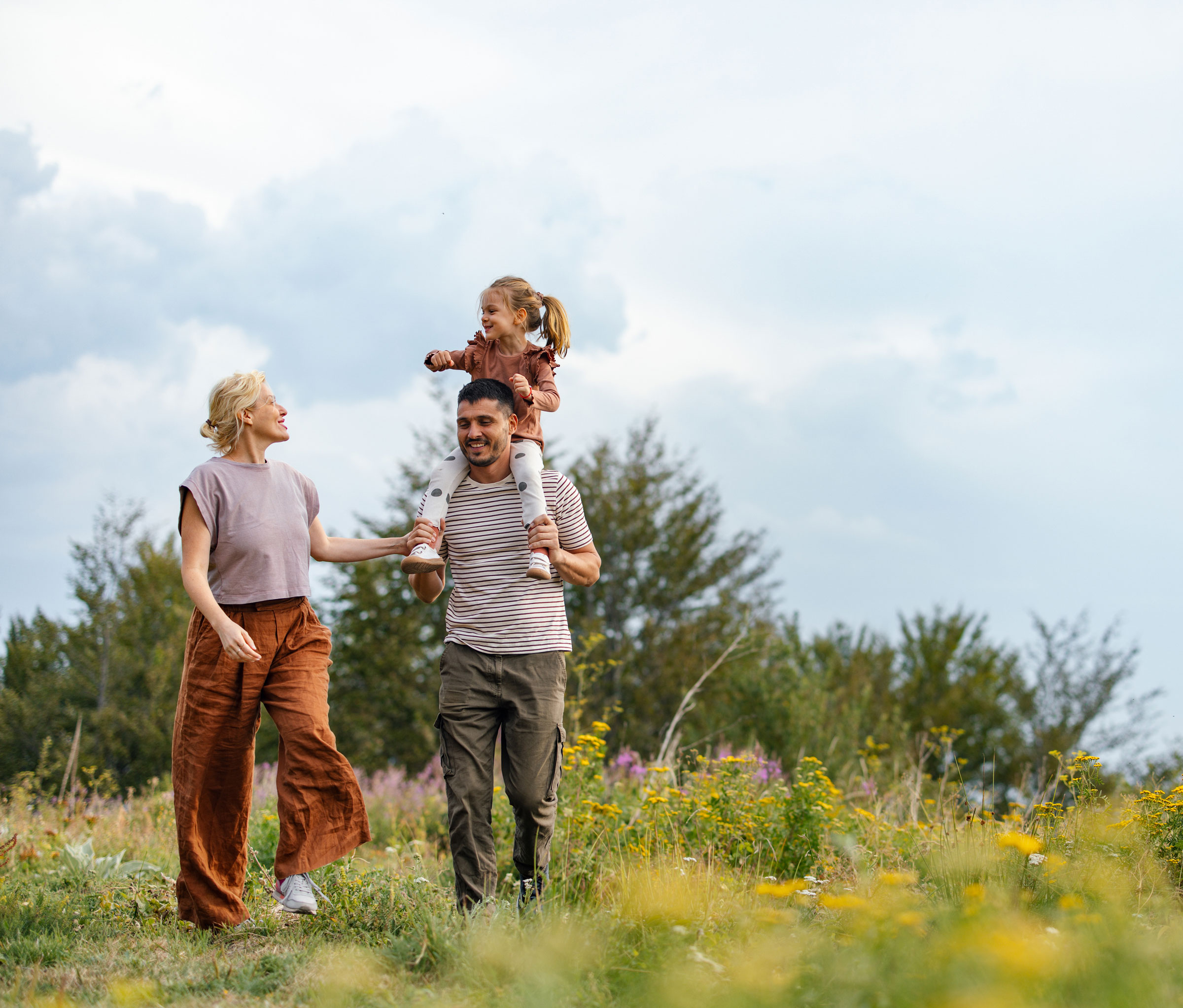 A young family goes for a walk through a field.