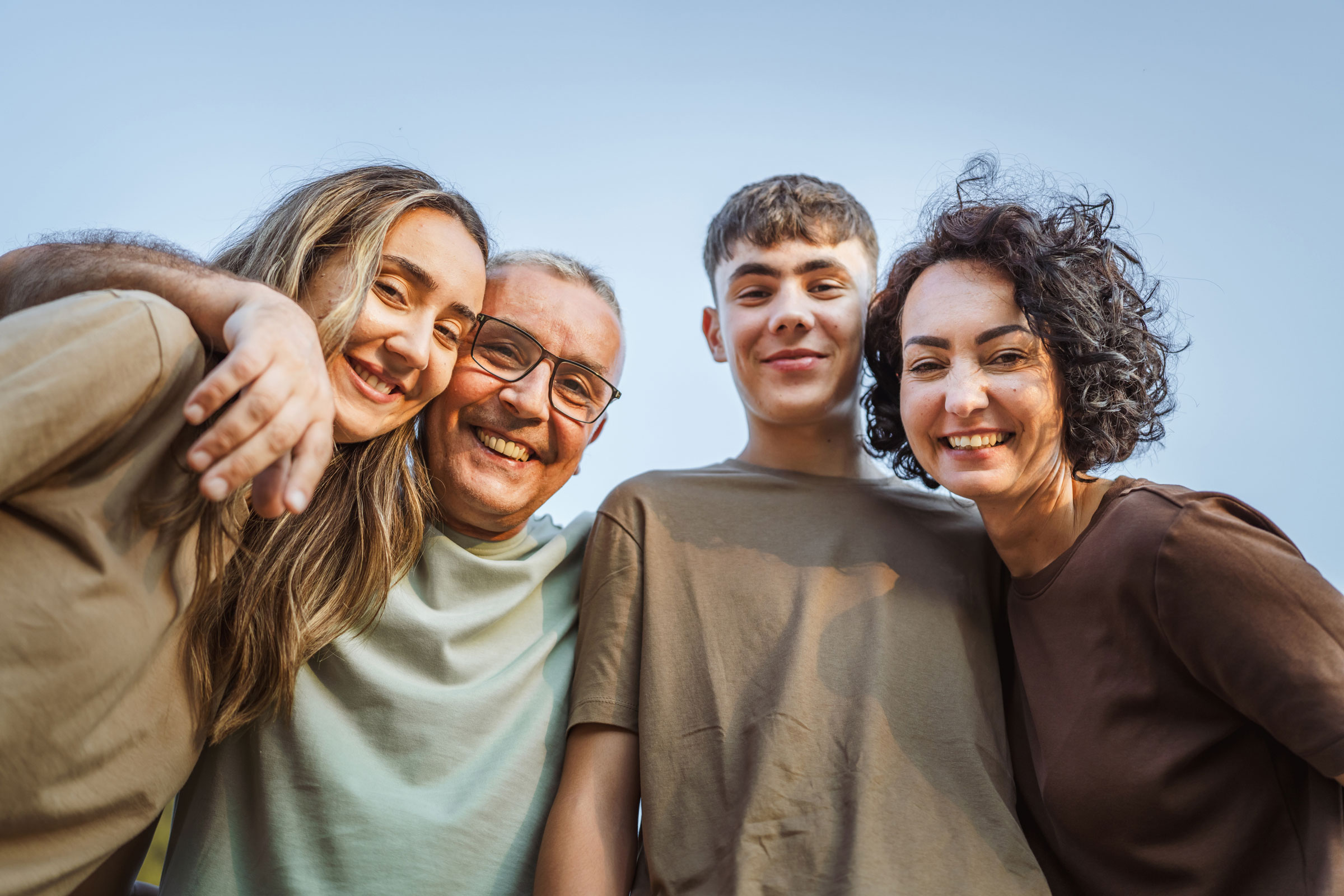 A family with teenagers smiles for the camera.